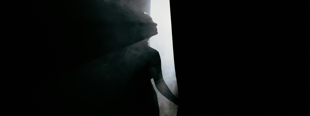 Silhouette of Woman Standing Behind a Curtain