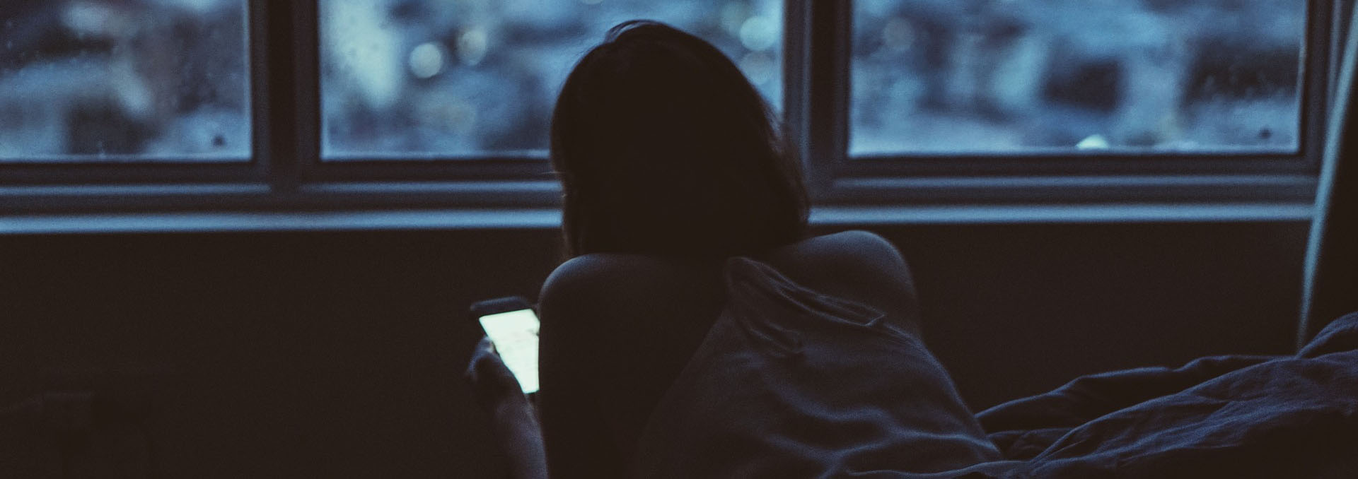 girl looking at her smartphone near windows